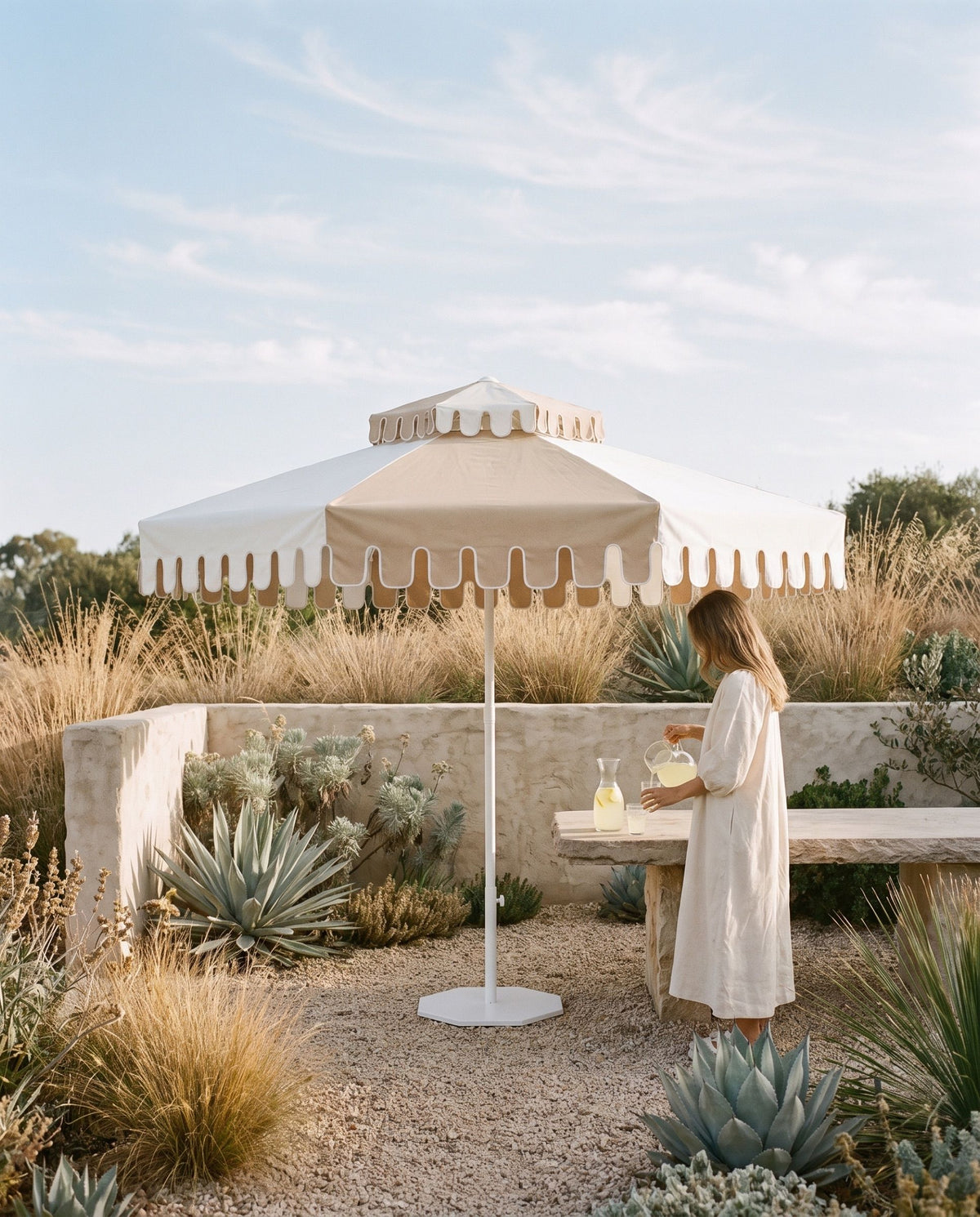 Lemonade poured at a stone table under a Desert Sand umbrella in a gravel garden