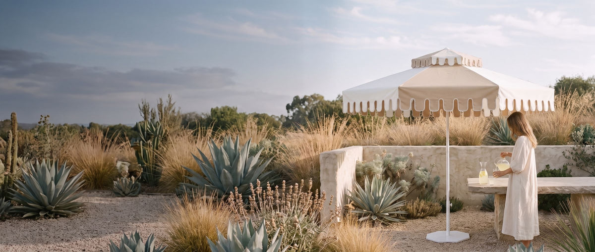 A Desert Sand umbrella on its base in a dry garden