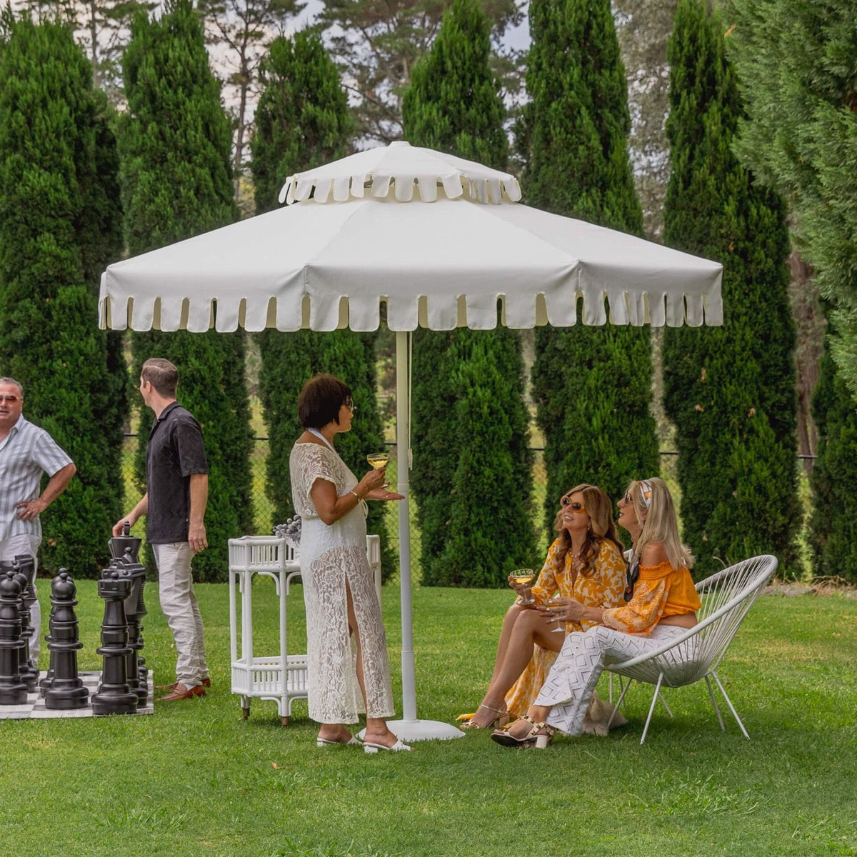 Guests under an Ivory Mist umbrella on a lawn, from our shoot